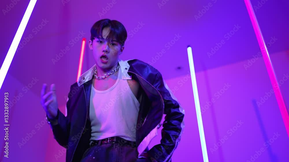 Low angle camera of professional street dancer looking at camera with casual cloth. Skilled performer moving to city pop music while standing at studio with purple led light. Close up. Regalement.