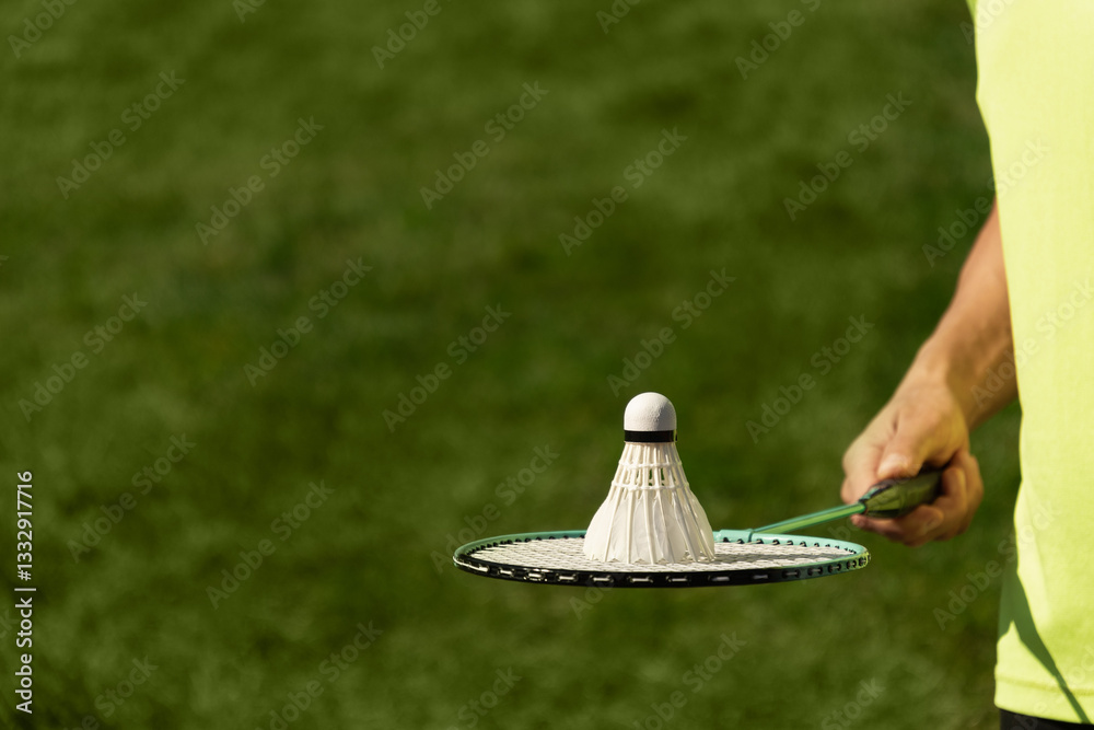White badminton shuttlecock and badminton racket in man hands. Summer sports game. Outdoor activity. Close up. Copy space.
