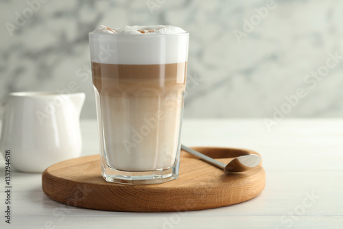 Tasty latte macchiato in glass on white wooden table, closeup