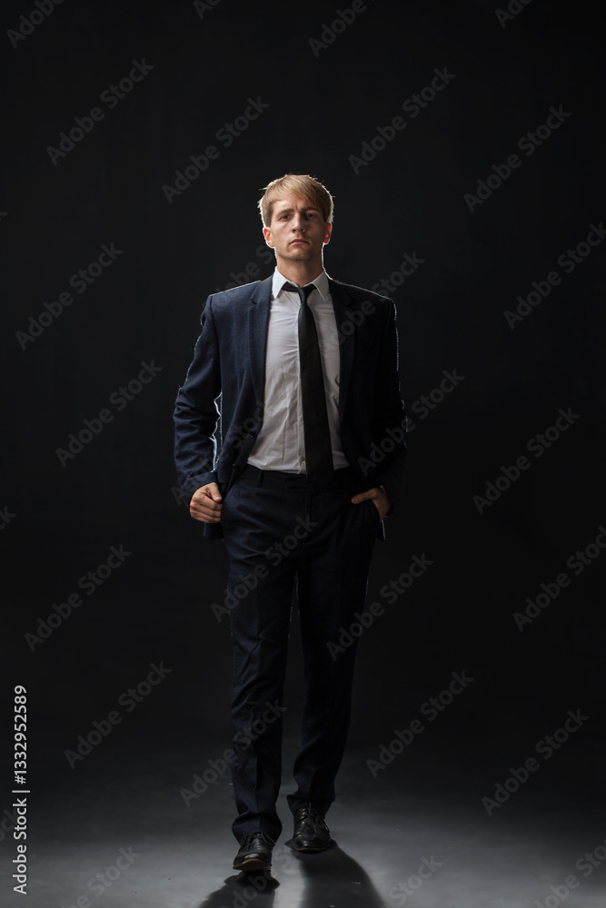 confident man strides forward in a dark suit, exuding authority and professionalism. The low-key, dark background highlights the formal attire in a corporate setting confident man strides forward in a dark suit, exuding authority and professionalism. The low-key, dark background highlights the formal attire in a corporate setting