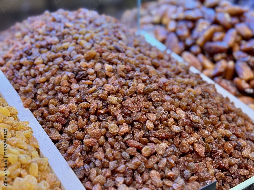 Close-up of a large mound of sun-dried brown raisins laid out on a tray for sale at a farmer's market in Uzbekistan