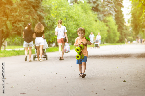 Wallpaper Mural A happy young boy walks along a park path on a bright day, clutching a toy car with excitement. Lush greenery and golden sunlight make this a perfect family outdoor moment. Torontodigital.ca