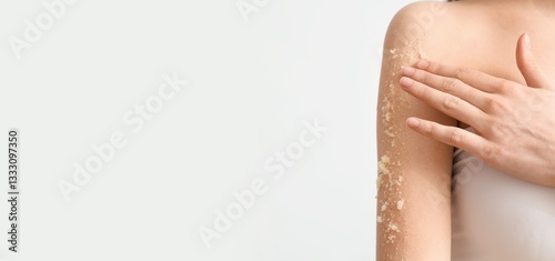 Young woman scrubbing her body against light background with space for text, closeup