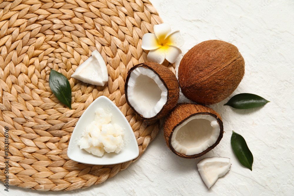 Wicker mat, flower and bowl with natural coconut oil on white background