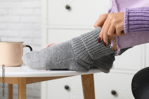 Woman in grey knitted socks sitting on chair at home, closeup