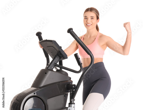 Sporty young woman training on modern exercising bike and showing muscles against white background