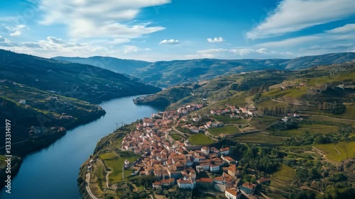 Scenic view of a river winding through a charming village surrounded by vineyards in a mountainous region during daylight hours