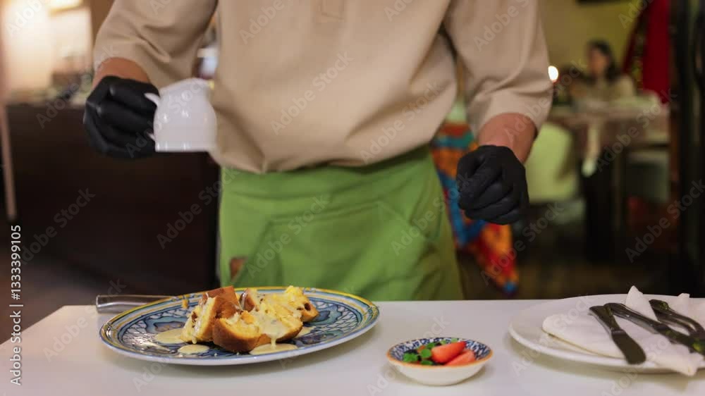 Waiter pouring condensed milk and adding berries on multiple pieces of panettone at restaurant Waiter pouring condensed milk and adding berries on multiple pieces of panettone at restaurant