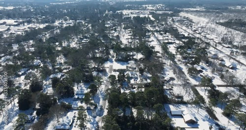 Aerial view flying over a small town community covered in snow on a sunny winter day after a blizzard