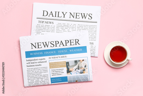Newspapers with cup of tea on pink background