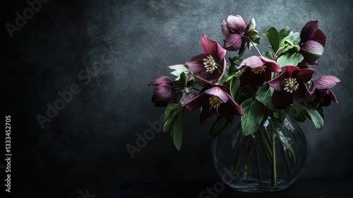 Dark and moody floral arrangement of hellebores in a glass vase, softly illuminated.