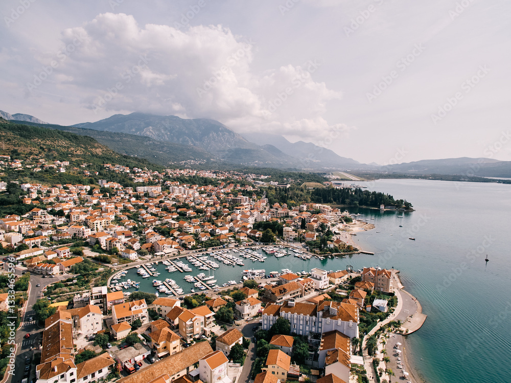 Fototapeta premium View over the red roofs of houses to rows of moored yachts. Porto, Montenegro. Drone
