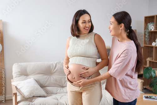 Young Asian doula with pregnant woman at home