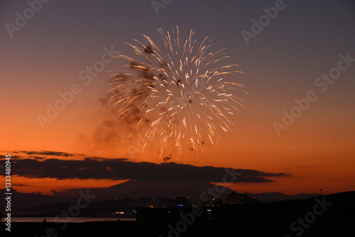 夕焼けの富士山のシルエットをバックに打ち上げられる花火