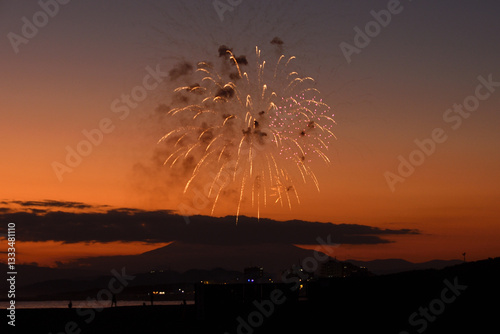 夕焼けの富士山のシルエットをバックに打ち上げられる花火