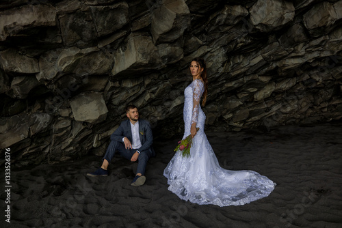 Imagine a breathtaking destination wedding scene set against the stunning backdrop of Reynisfjara Black Sand Beach in Iceland, where a beautiful bride and her handsome groom celebrate their love