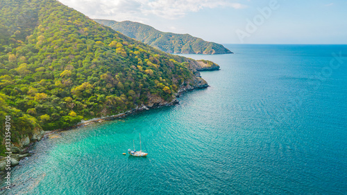 Stunning Aerial View of Tayrona National Park in Santa Marta, Magdalena, Colombia with a Sailboat in Crystal Clear Waters