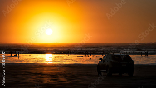 A breathtaking sunset casts golden hues over a serene beach, while silhouettes of people enjoy the tranquil setting, evoking feelings of relaxation and joy.