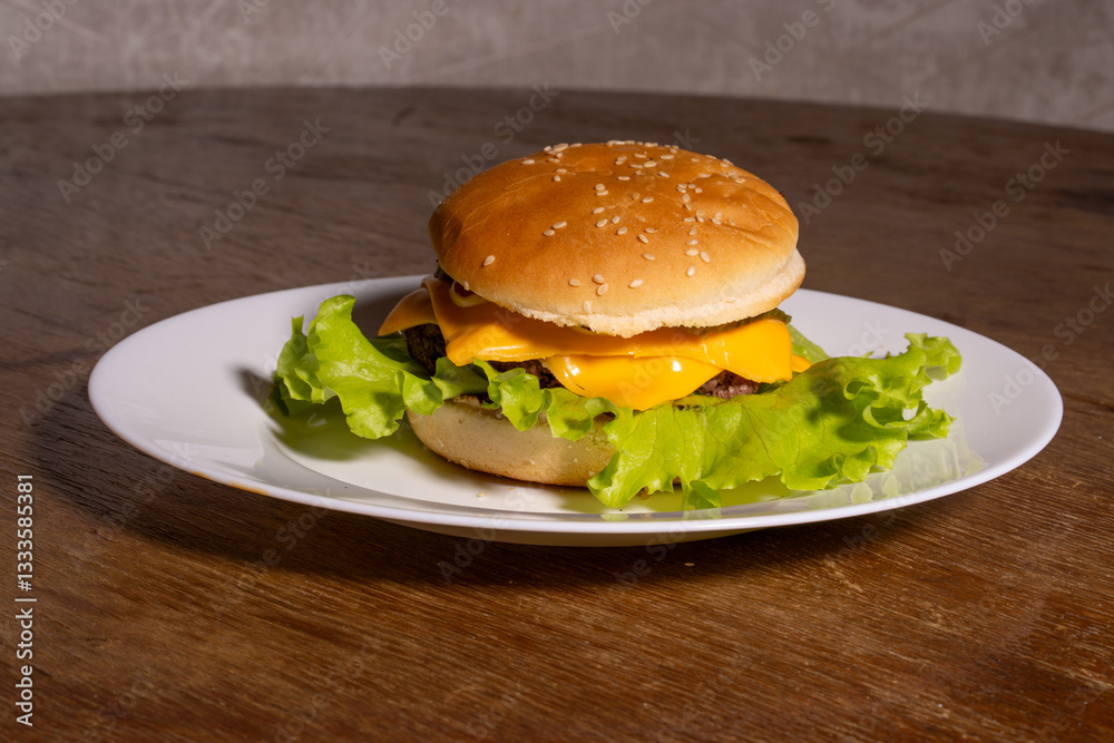 A juicy cheeseburger with a sesame seed bun, melted cheese, beef patty, and lettuce on a white plate, styled atop a rustic wooden background.