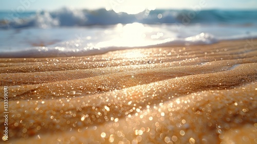 Close-up of wet golden sand on a beach, sunlit waves in the background.
