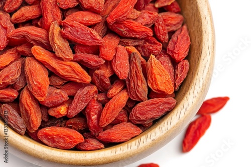 Dried goji berries overflowing a small wooden bowl