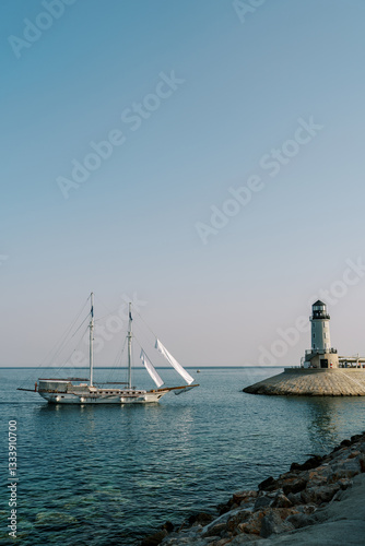 Wallpaper Mural White sailboat moored in the sea near the lighthouse on the cape Torontodigital.ca