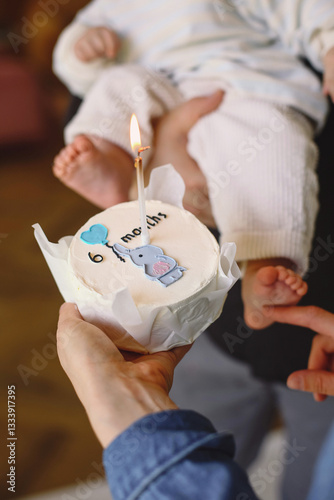Happy family celebrating son's 6 month birthday.  Young parents joyfully present cake to baby