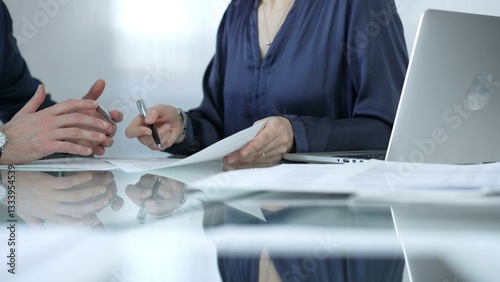 Business colleagues analyzing financial data and collaborating on a project during a productive office meeting while sitting at the glass table. Businesspeople concept