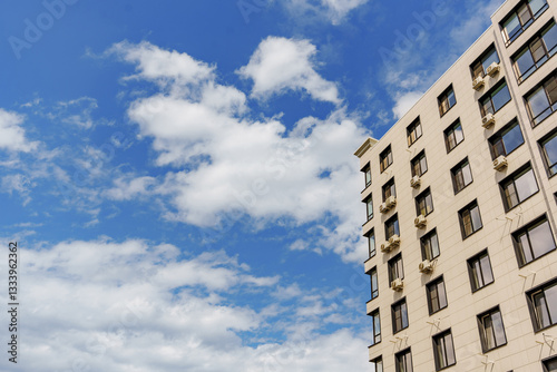 A multi-storey modern building against the background of the sky with clouds.
