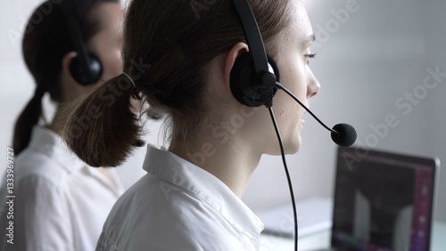 Obraz na płótnie Young female call center operator in white blouse is assisting clients online, providing customer support and answering inquiries. Business call center w salonie