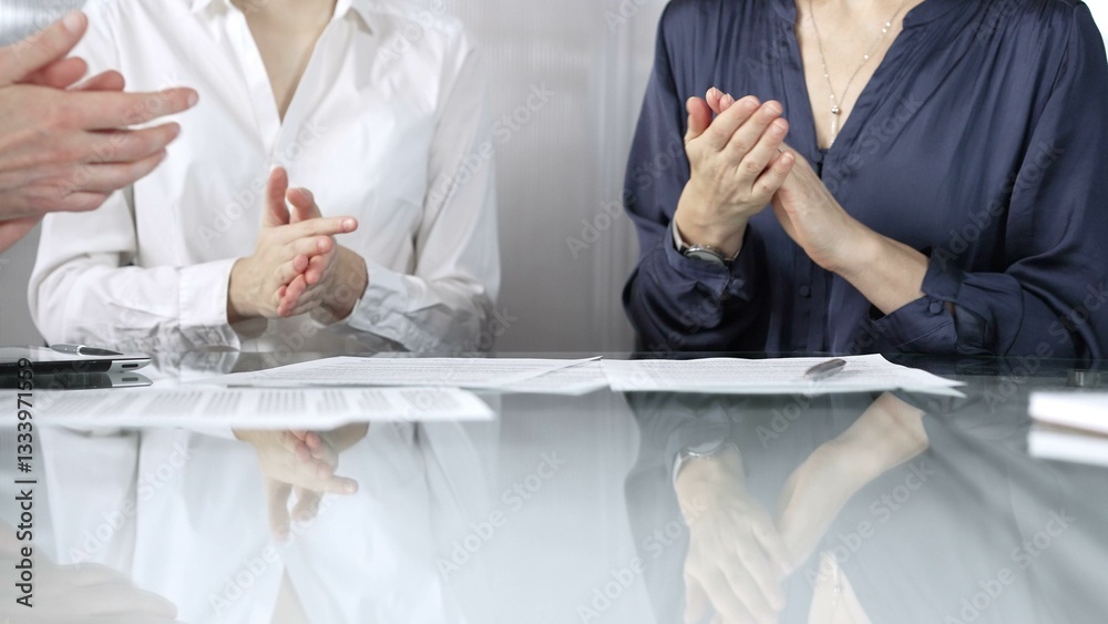 Unrecognizable business professionals applauding and celebrating achievements at glass table after successful meeting. Business people concept, close up view