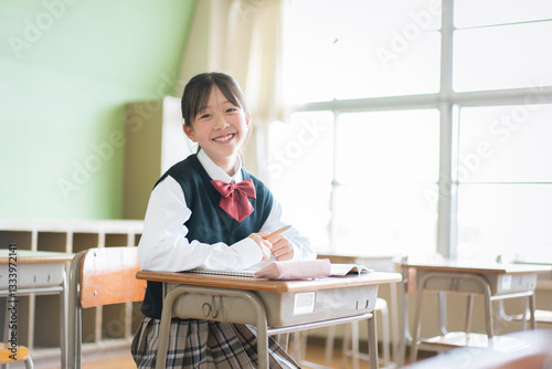 教室の中で座っている笑顔の女子中学生