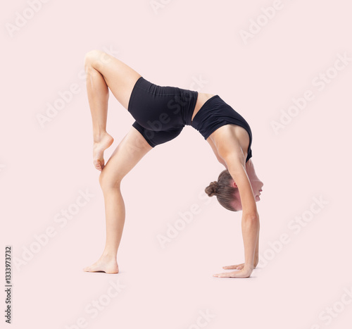Fototapeta Naklejka Na Ścianę i Meble -  Young woman doing artistic gymnastics training, flexible rhythmic gymnast performing poses and showing skills and talent, sport workout, fitness and Well-Being concept, isolated on pink background