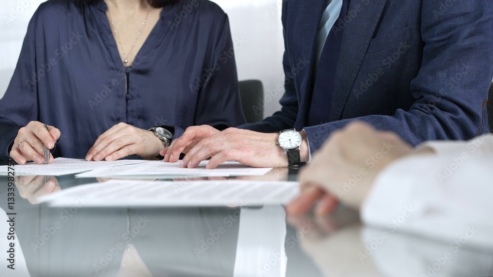 Business people reviewing contract terms while sitting at the glass desk during a meeting, negotiation in office, close up view. Success concept