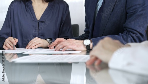 Obraz na płótnie Business people reviewing contract terms while sitting at the glass desk during a meeting, negotiation in office, close up view. Success concept w salonie