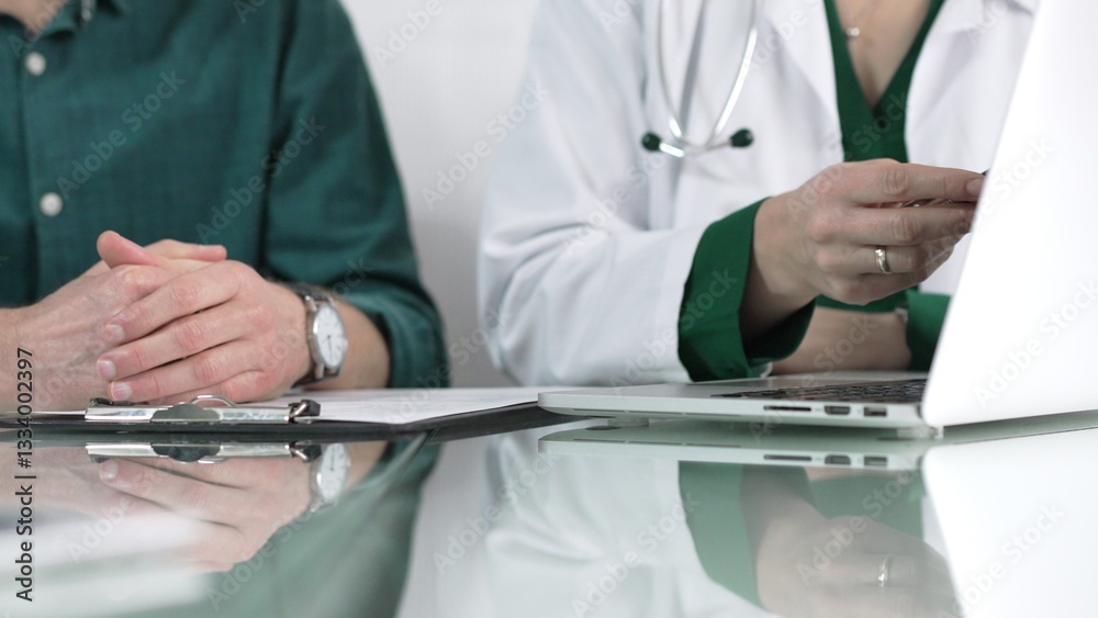 Female doctor showing medical exam results on a laptop to a patient during a visit at the clinic, healthcare and medical consultation concept