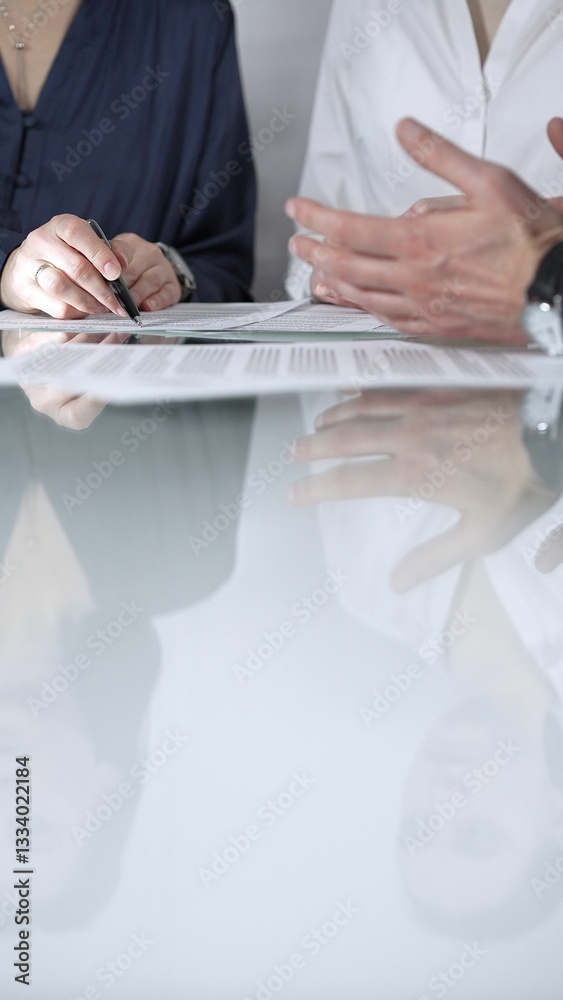 Business people are reviewing contract terms during a meeting, negotiating and making decisions together, vertical close up view. Copy space area
