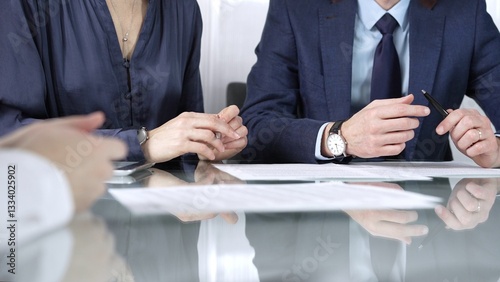 Business partners or lawyers are reviewing contract terms during a meeting, negotiating and making decisions together. Business people concept, close up view