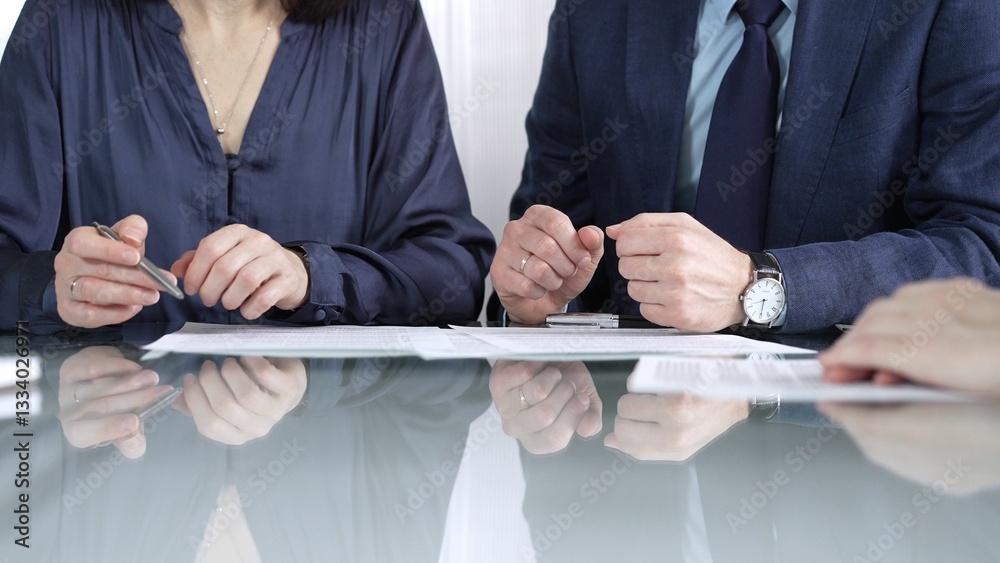 Business partners or lawyers are reviewing contract terms during a meeting, negotiating and making decisions together. Business people concept, close up view