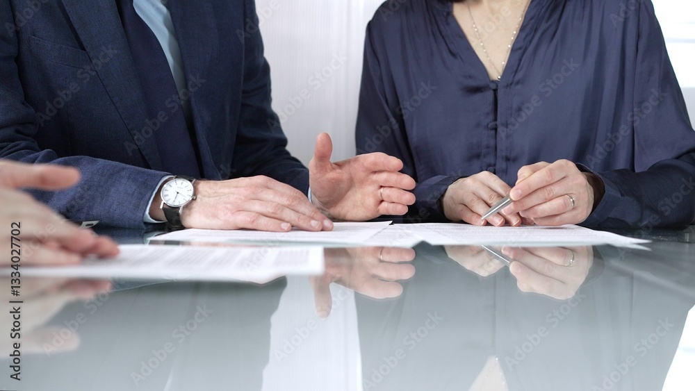 Business people reviewing contract terms while sitting at the glass desk during a meeting, negotiation in office, close up view. Success concept