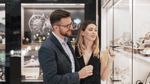 Beautiful couple enjoying in shopping at modern jewelry store. Close up shot of woman's hand with gorgeous expensive ring and bracelet.