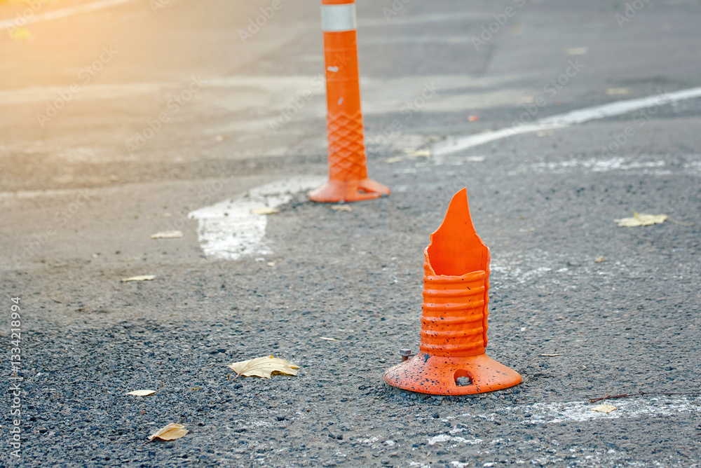 Damaged traffic cone with cracks and missing sections stands useless as an anti-parking barrier, urban decay and the need for road maintenance. Damaged traffic cone needs replacement for safety