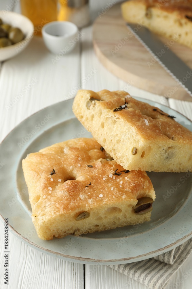 Pieces of delicious focaccia bread with olives, thyme and salt on white wooden table, closeup Pieces of delicious focaccia bread with olives, thyme and salt on white wooden table, closeup