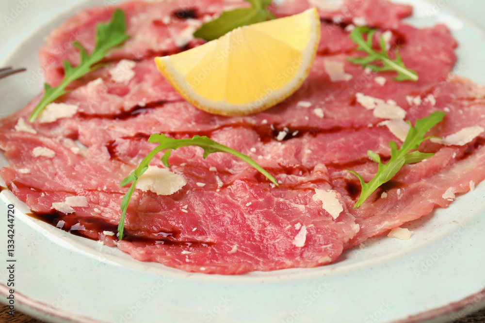 Delicious beef carpaccio with arugula, cheese, balsamic vinegar and lemon on plate, closeup Delicious beef carpaccio with arugula, cheese, balsamic vinegar and lemon on plate, closeup
