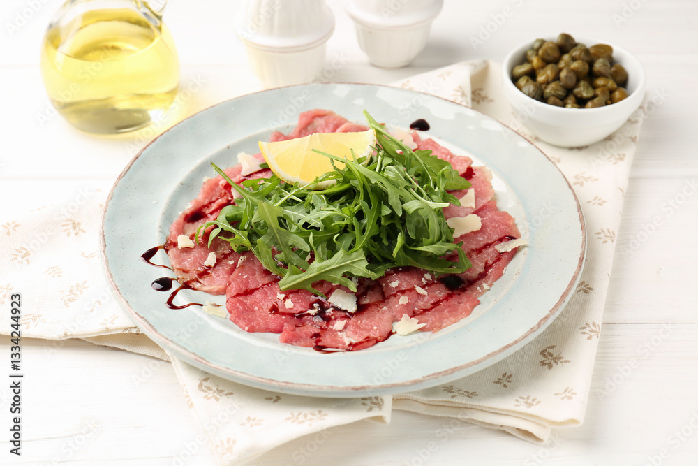 Delicious beef carpaccio with arugula, lemon, capers and oil on white wooden table, closeup Delicious beef carpaccio with arugula, lemon, capers and oil on white wooden table, closeup