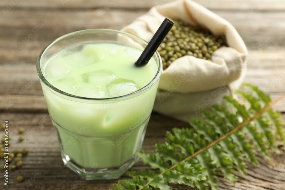 Fresh mung bean juice with ice in glass, leaves and seeds on wooden table, closeup Fresh mung bean juice with ice in glass, leaves and seeds on wooden table, closeup