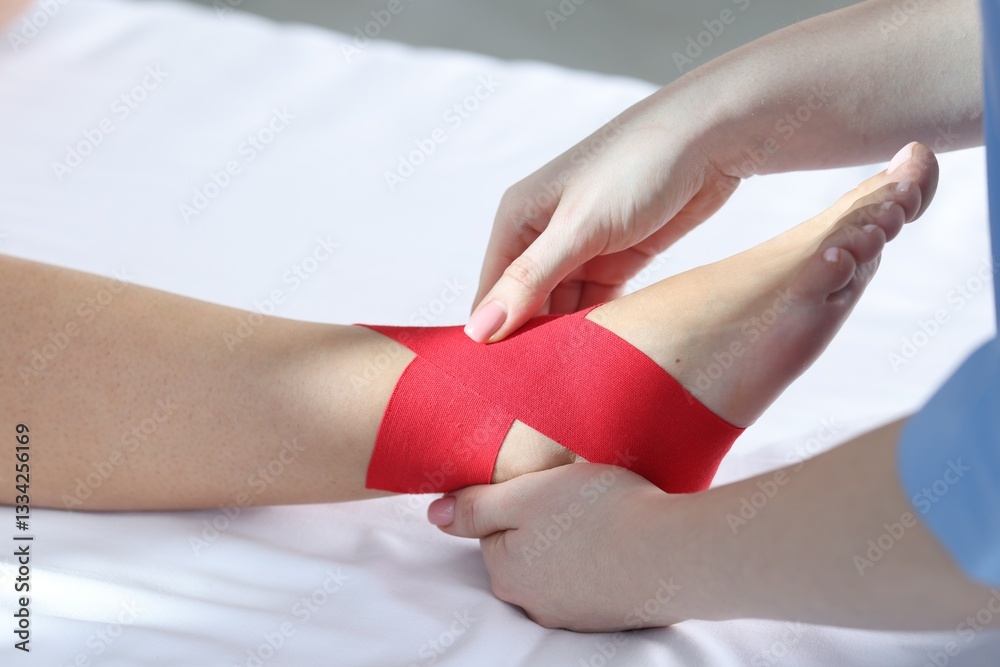 Obraz premium Doctor applying kinesio tapes to patient's foot in hospital, closeup
