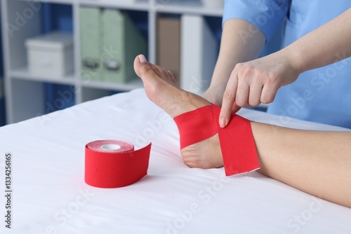 Doctor applying kinesio tapes to patient's foot in hospital, closeup