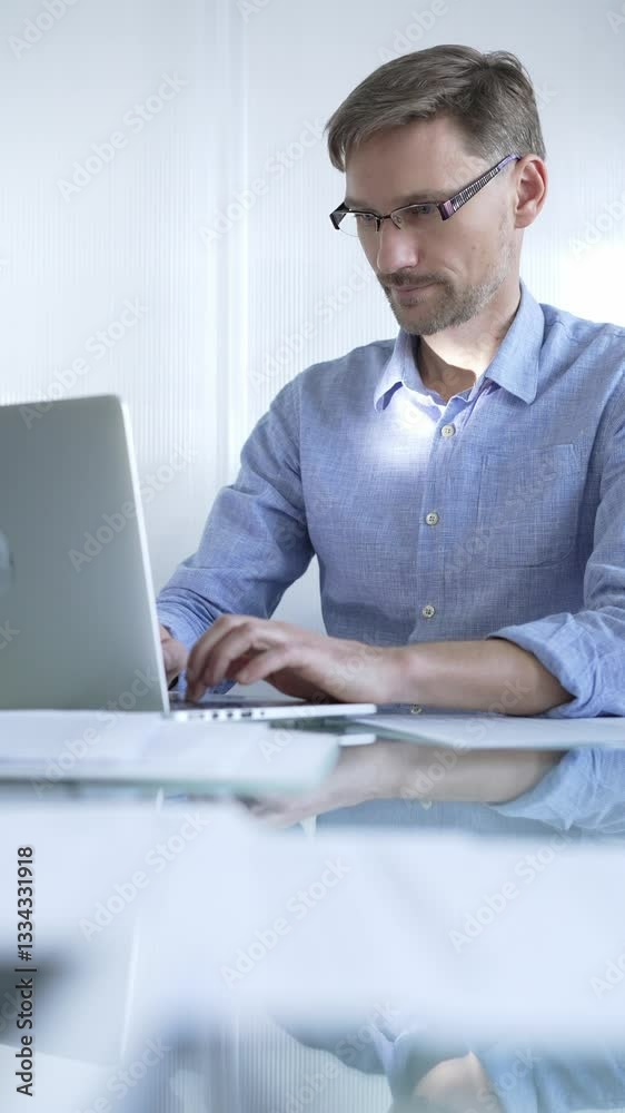 Casual dressed businessman is using a laptop in a contemporary office, with a clean, bright environment that boosts efficiency. Business people concept Casual dressed businessman is using a laptop in a contemporary office, with a clean, bright environment that boosts efficiency. Business people concept