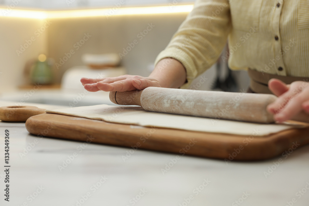 Obraz premium Woman rolling dough at light table indoors, closeup. Making croissants